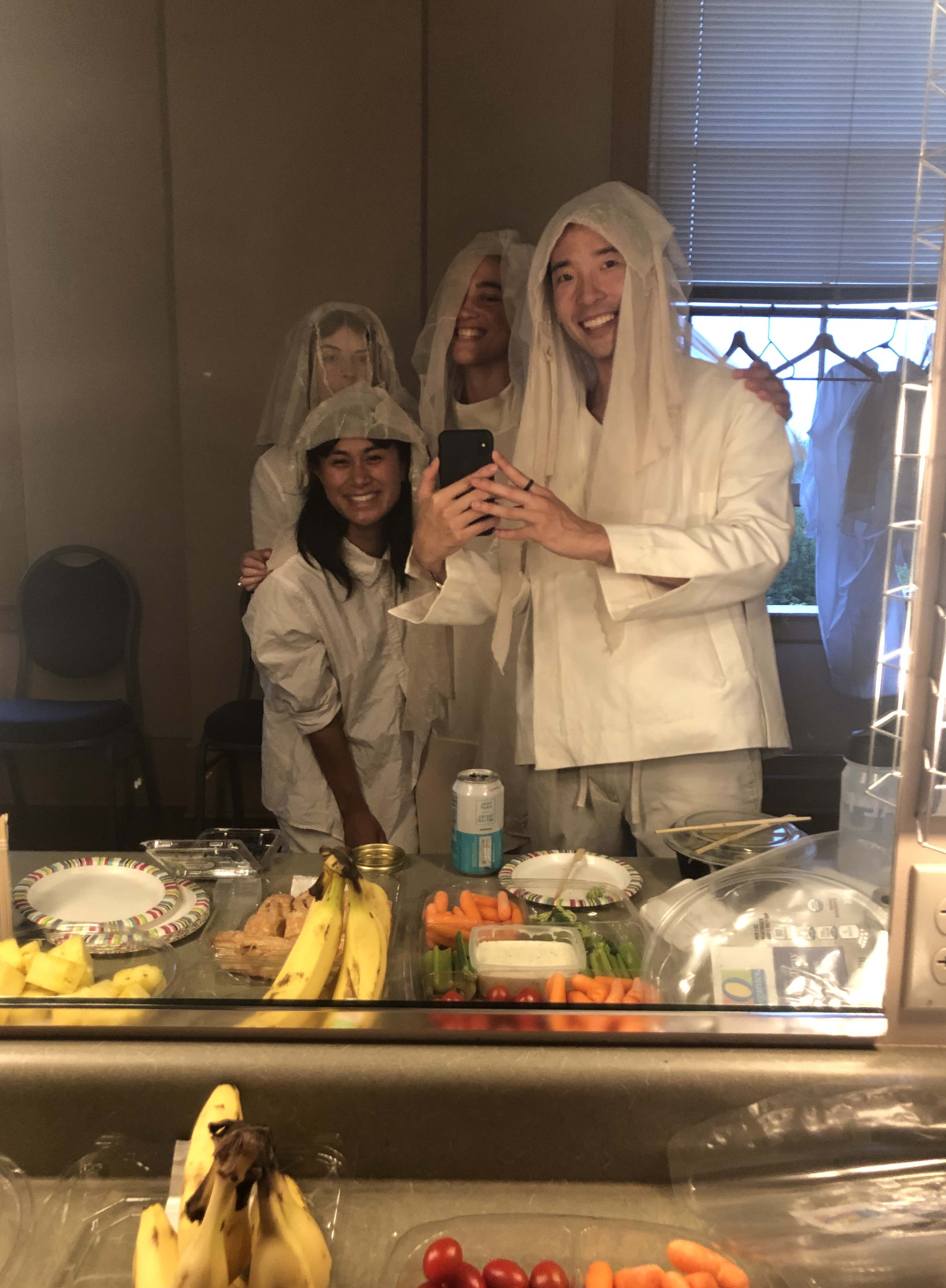 Performers in white garments posing together after performance