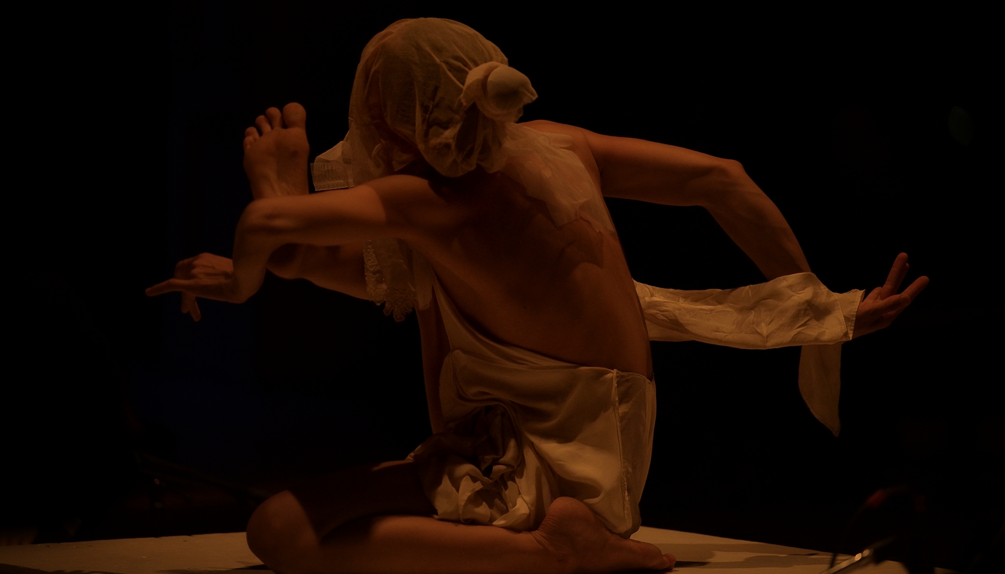 Katrina Wolfe performing movement on stage at Chapel Performance Space in low blue light