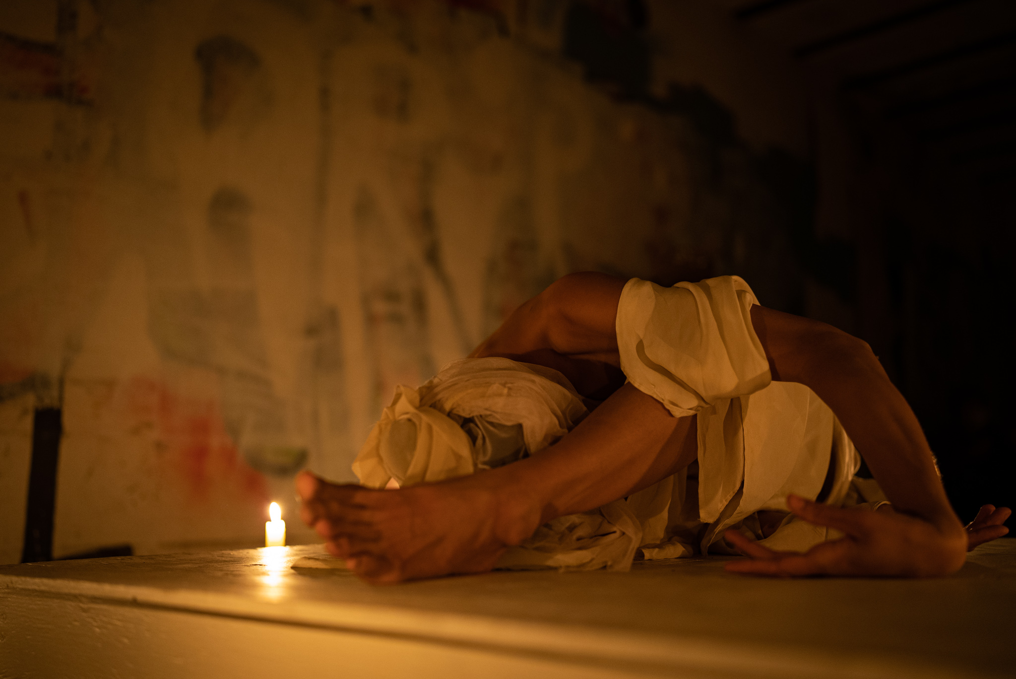 Katrina Wolfe performing movement on a raised platform by candlelight inside Battery John Brannon