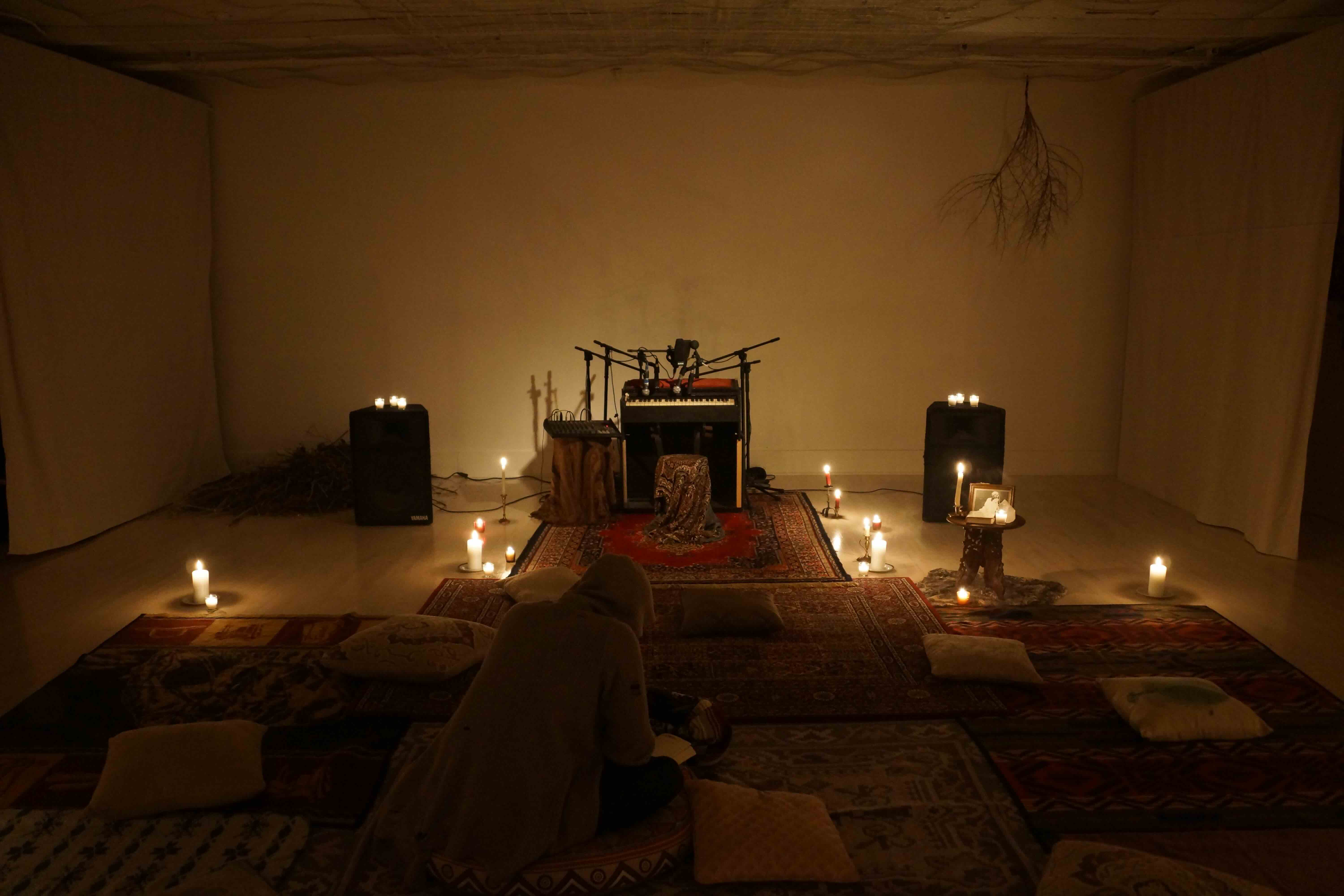 Wide view of Studio Ma installation with candles and rugs