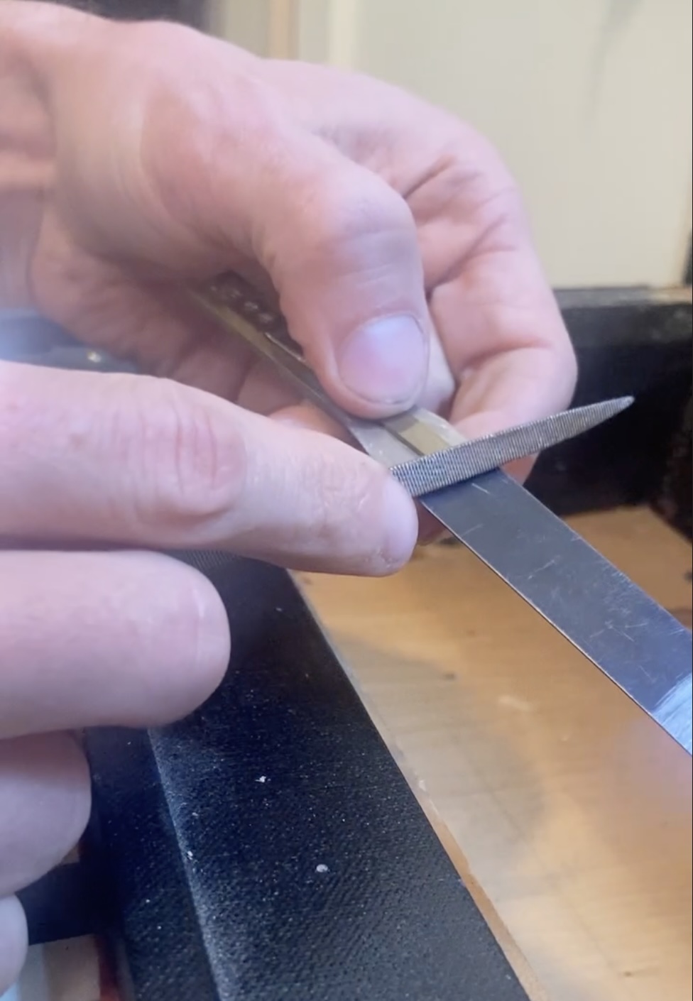 Close-up of reed organ tuning process using a metal file on a reed tongue
